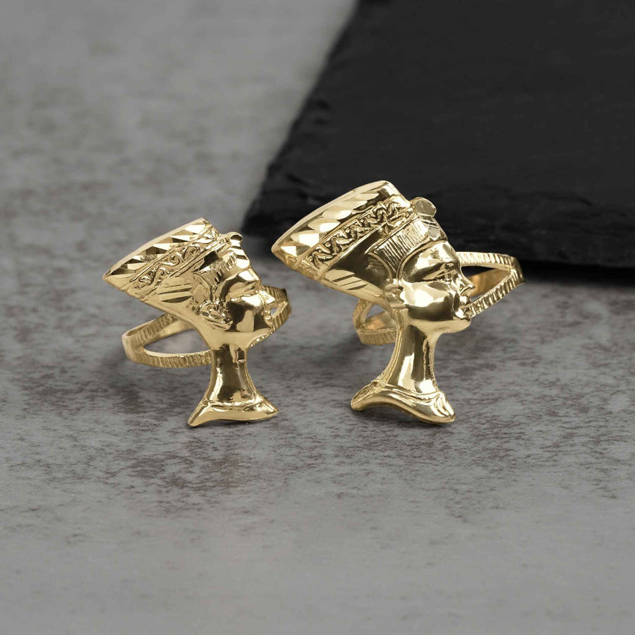 Two 10k gold classic Nefertiti profile rings displayed on a gray stone surface.