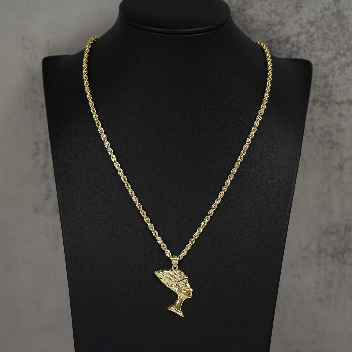Polished 10k gold Queen Nefertiti pendant hanging on a rope chain, displayed on a bust.