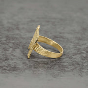 Side view of 10k gold classic Uzi ring showcasing textured details on gray surface.