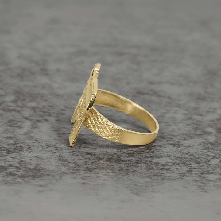 Side view of 10k gold classic Uzi ring showcasing textured details on gray surface.