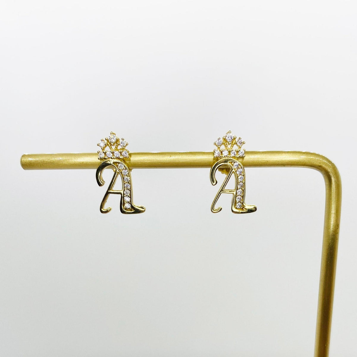 Pair of 10k yellow gold cursive A initial stud earrings featuring sparkling CZ crowns.