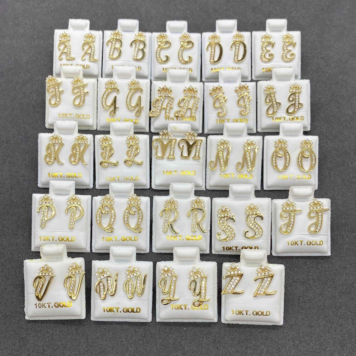 Complete alphabet set of 10k yellow gold cursive initial stud earrings featuring sparkling CZ crowns.