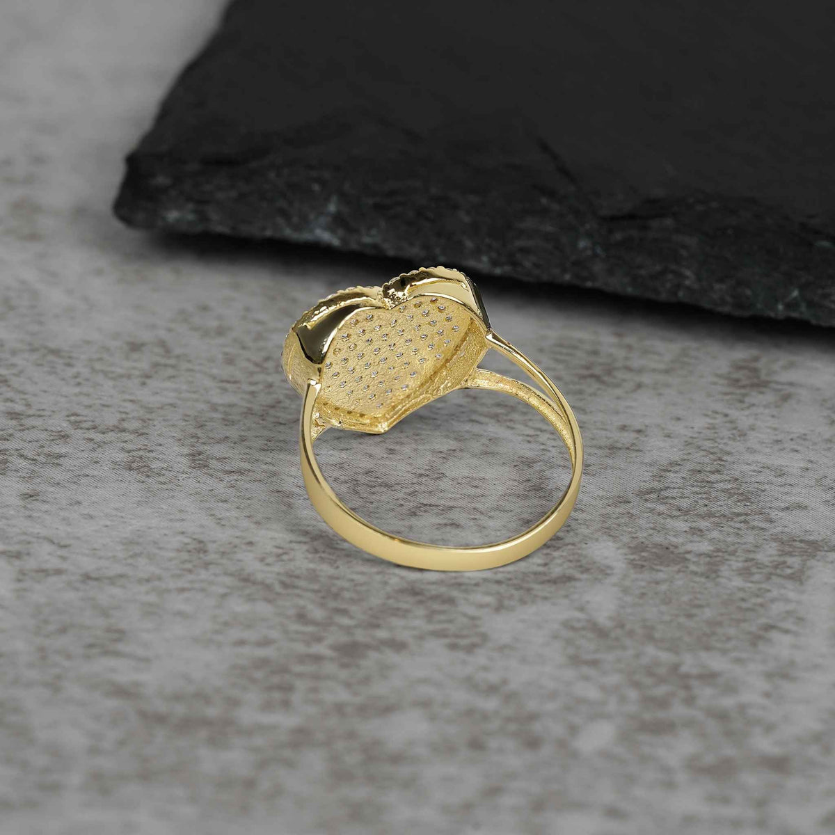 Side-back profile of a yellow gold ring revealing the open-back pavé heart setting.