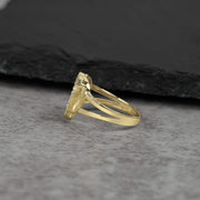 Side and back view of a yellow gold heart-shaped ring on a gray surface.