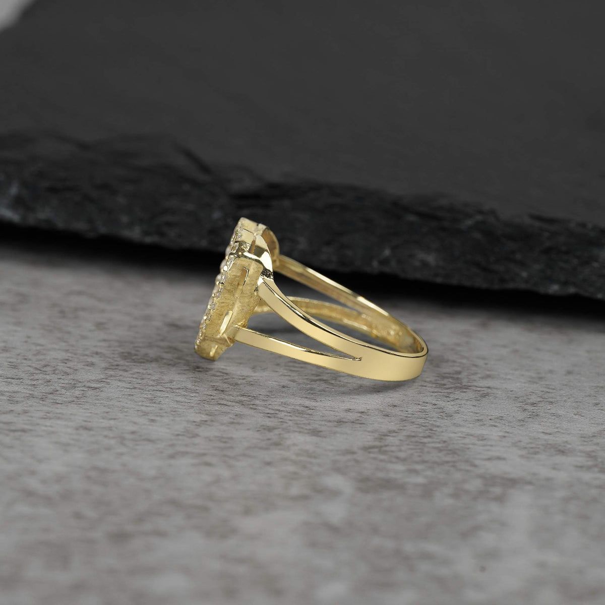 Side and back view of a yellow gold heart-shaped ring on a gray surface.