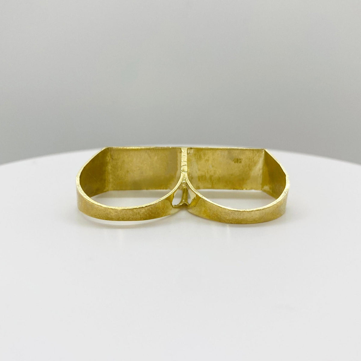 10k Gold double finger ring back view on a white plate with a gray background