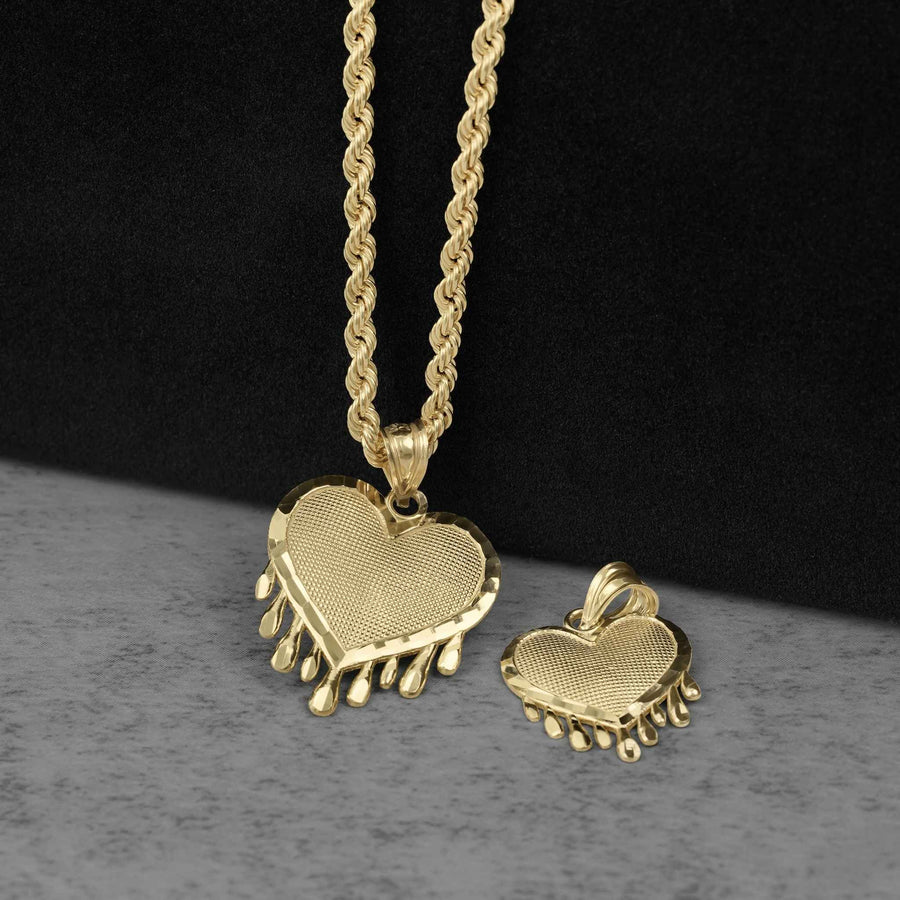 A gold heart pendant with dripping details next to a smaller matching pendant on a chain.