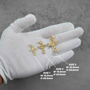 Gloved hand displaying three different sizes of gold cross pendants with size dimensions.