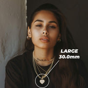 Woman wearing layered gold necklaces showcasing a large 30.0mm heart pendant.