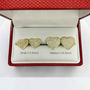 Size comparison of small 12.5mm and medium 14.5mm 10k gold heart-shaped CZ stud earrings.