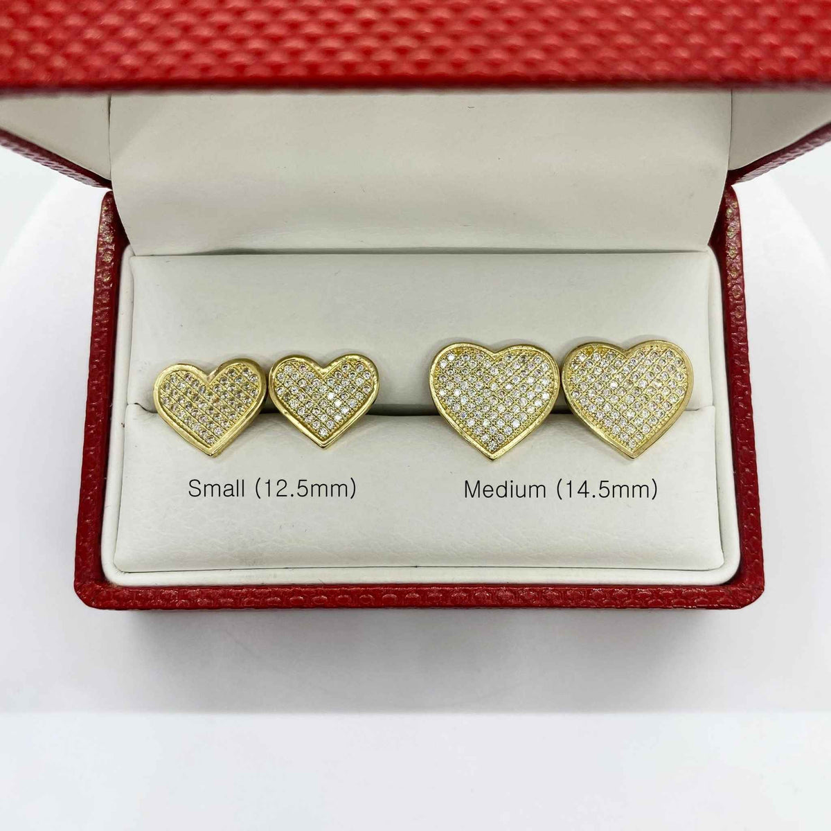 Size comparison of small 12.5mm and medium 14.5mm 10k gold heart-shaped CZ stud earrings.