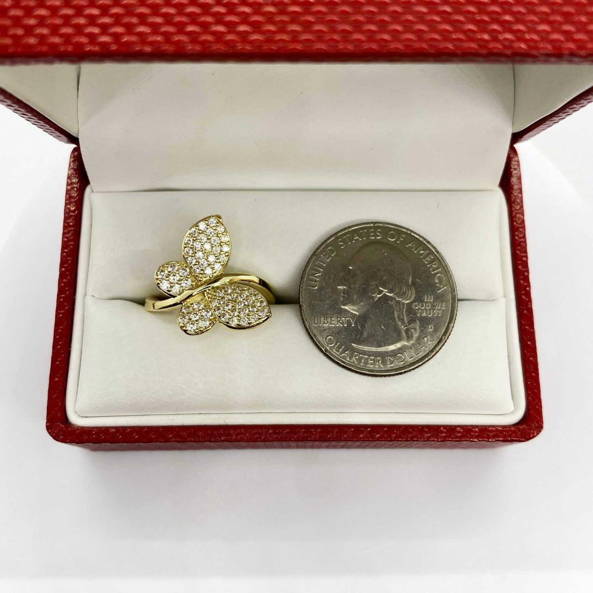 10k Gold Gleam butterfly ring next to a quarter in an open red jewelry box.