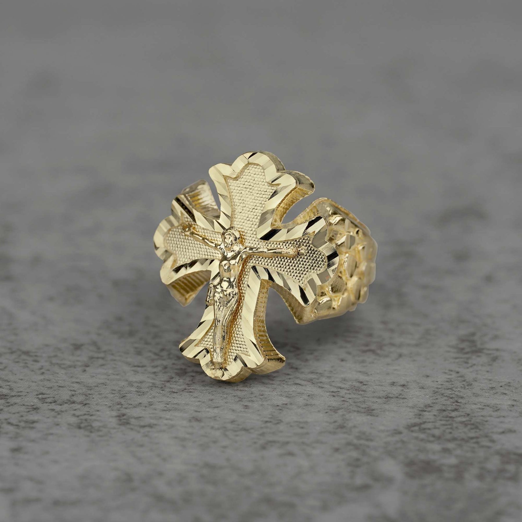 10k gold gothic crucifix nugget Ring on a gray textured background