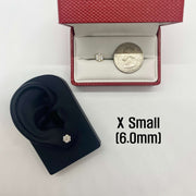 Gold hexagon flower cubic zirconia earring next to a quarter and black ear model.