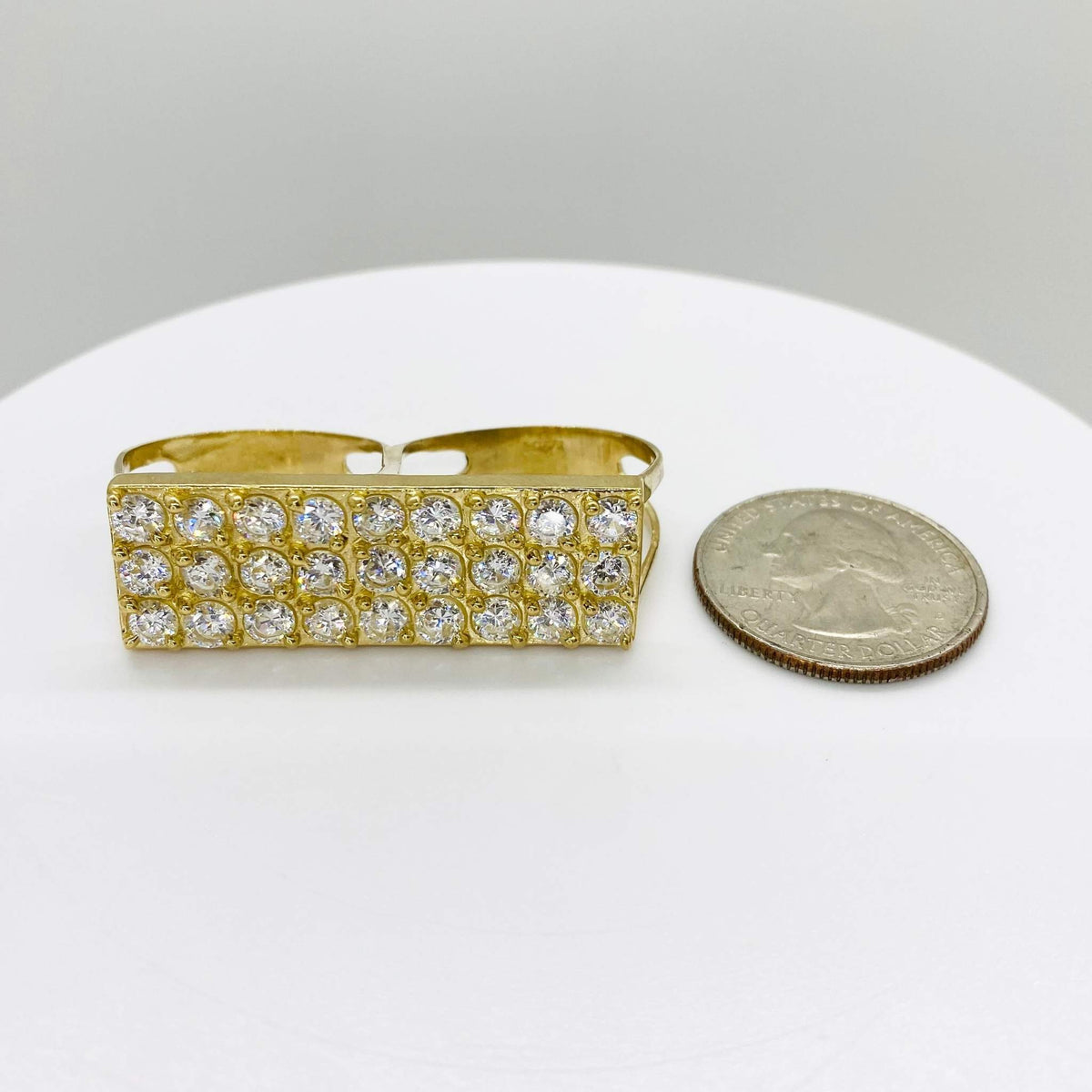 10k Gold two finger ring with rectangular design next to a quarter on a white surface