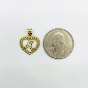 10k yellow gold initial A Rollie heart pendant next to a US quarter for size comparison.