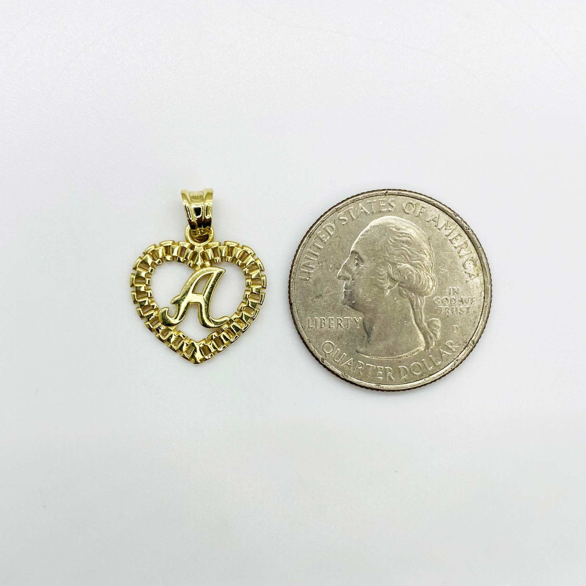 10k yellow gold initial A Rollie heart pendant next to a US quarter for size comparison.