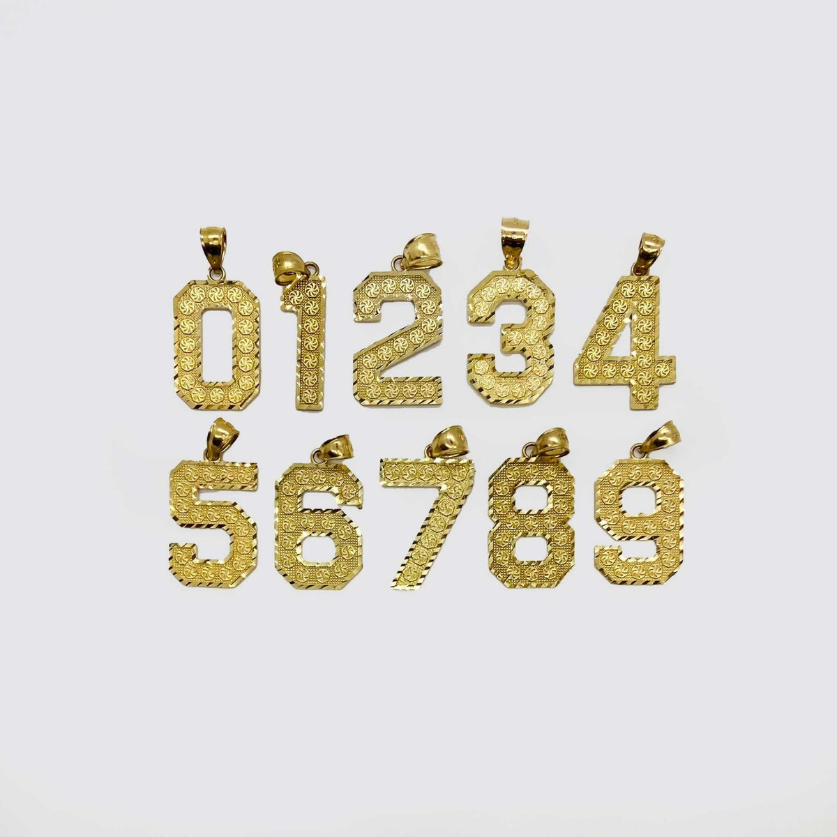 Ten textured yellow gold number pendants, zero through nine, arranged on a light background.