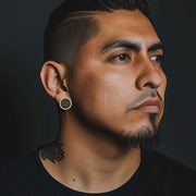Man wearing 10k yellow gold jumbo round stud earrings with black cubic zirconia.