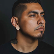Man wearing 10k yellow gold jumbo round stud earrings with white cubic zirconia.