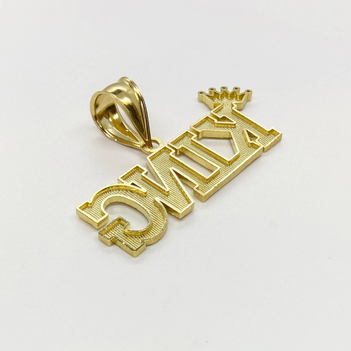 Reverse side of 10k yellow gold diamond-cut King word pendant on white background.