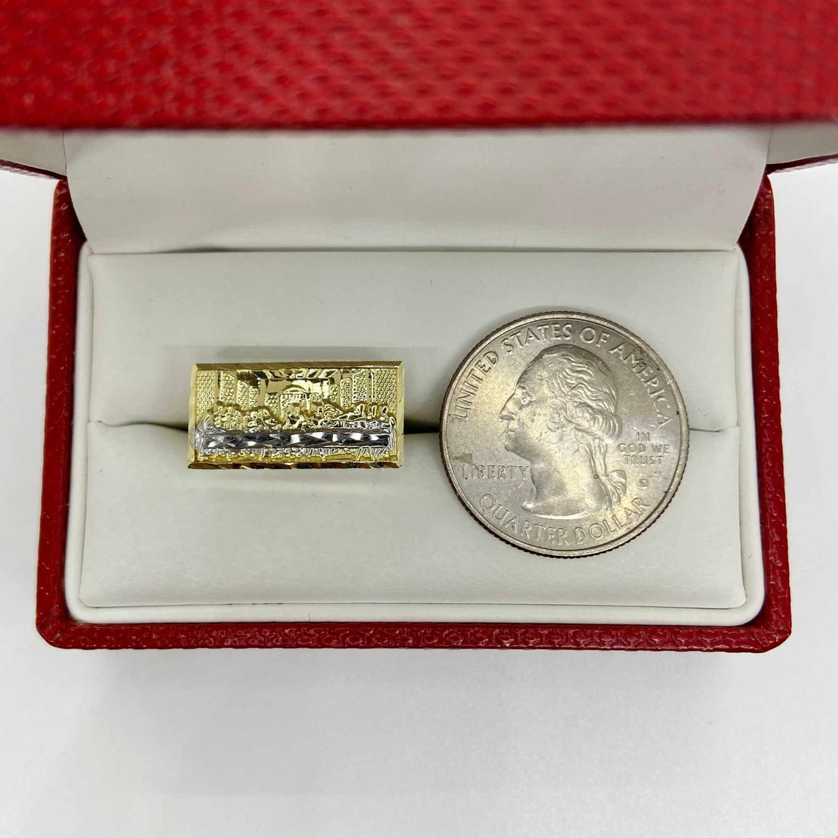 10k Gold ring with Last Supper design next to a silver dollar coin.