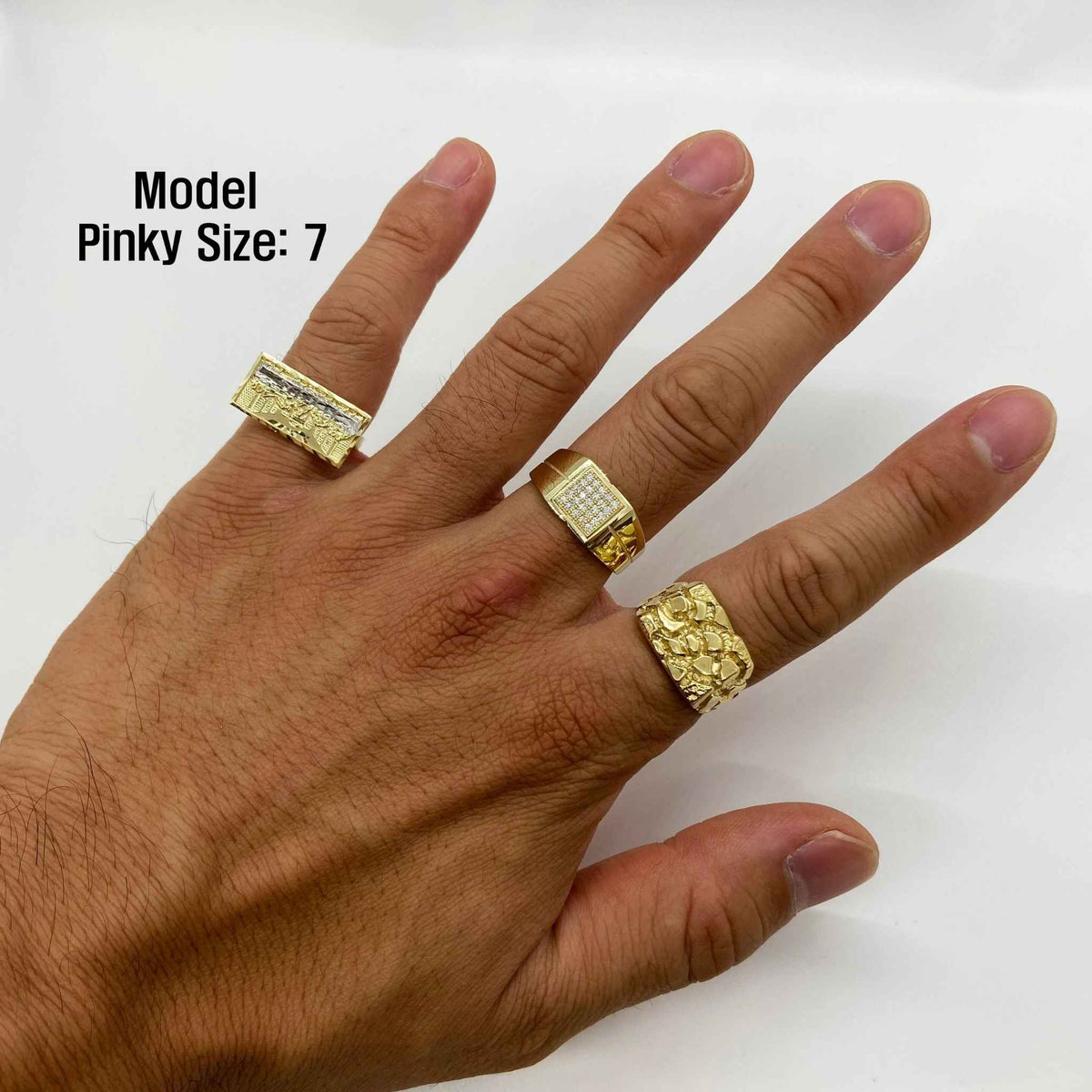 Hand wearing three gold rings with a plain background
