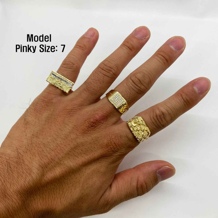 Hand wearing three gold rings with a plain background