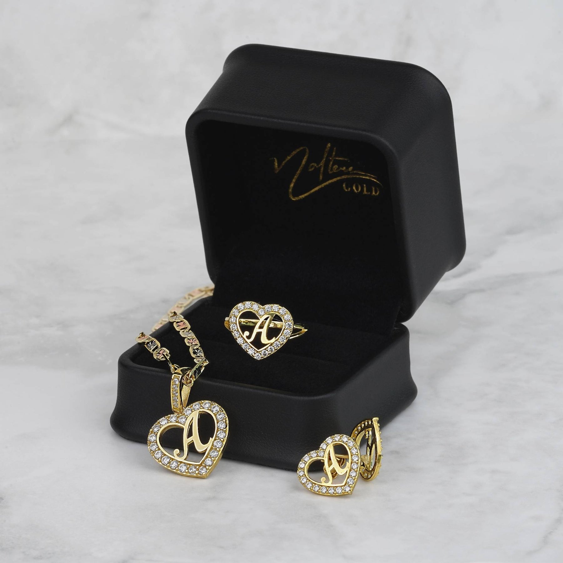 Gold heart-shaped jewelry set including a necklace pendant, ring, and earrings with letter 'A'.