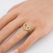 Yellow gold initial heart ring with sparkling cubic zirconia crystals styled on a finger.