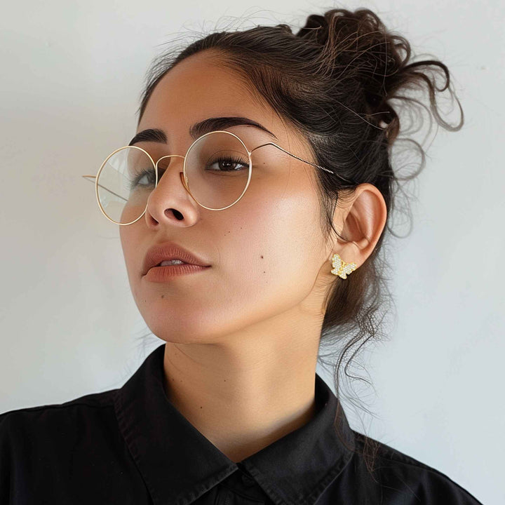 Model wearing 10k gold butterfly-shaped stud earrings with cubic zirconia.