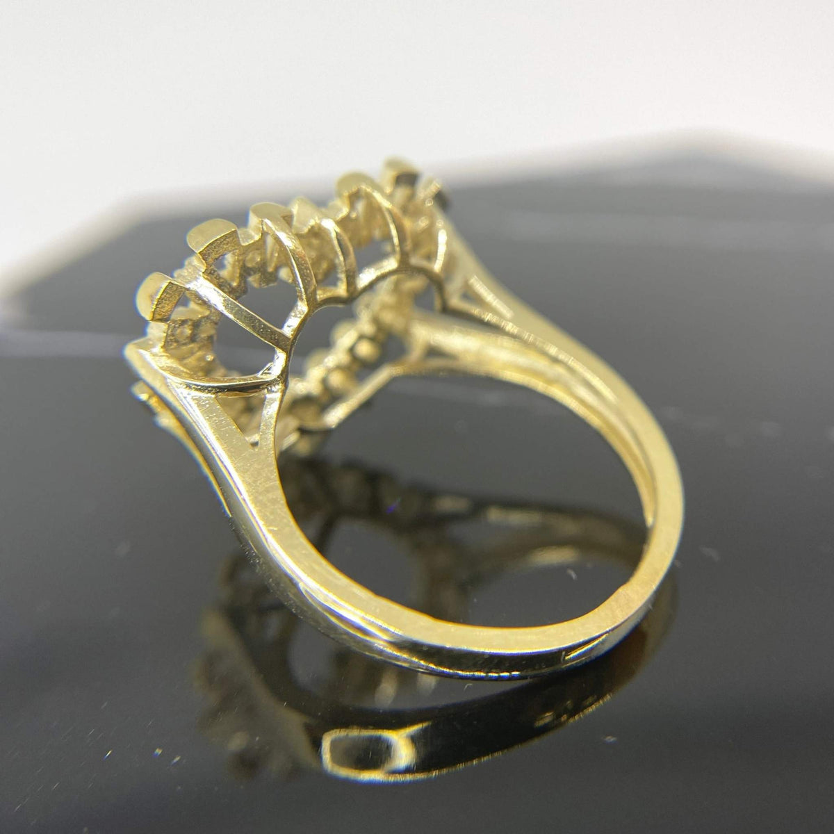 10k Gold ring with intricate design back view on a reflective black surface