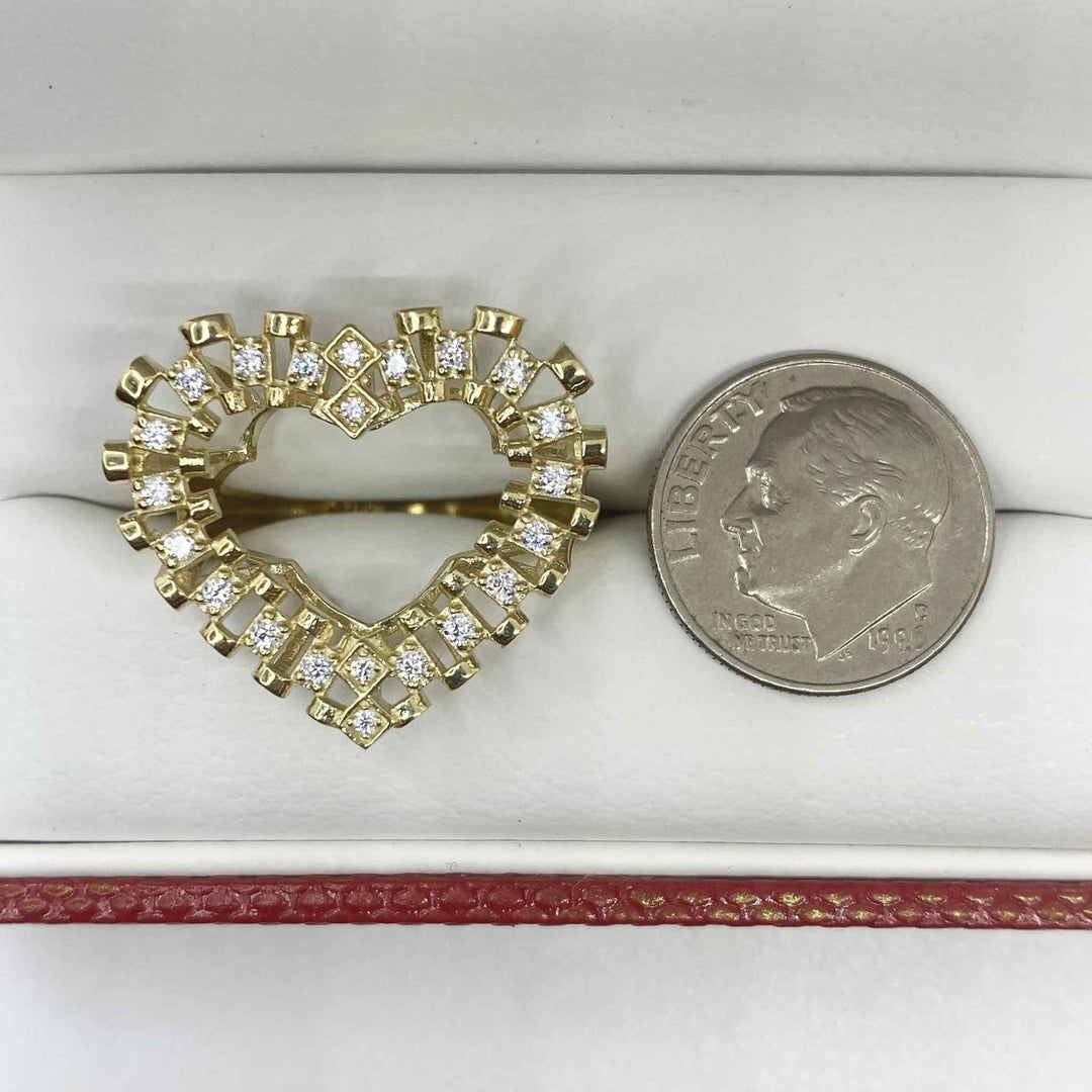 10k Gold heart shaped ring with Cubic Zirconia next to a quarter for comparison on a white surface.