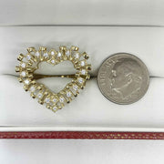 10k Gold heart shaped ring with Cubic Zirconia next to a quarter for comparison on a white surface.