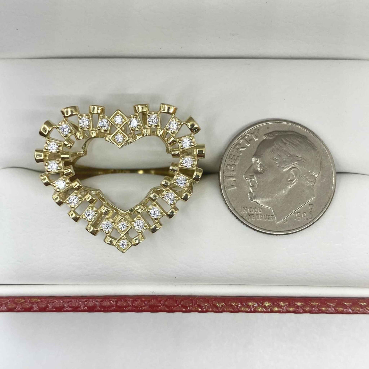 10k Gold heart shaped ring with Cubic Zirconia next to a quarter for comparison on a white surface.