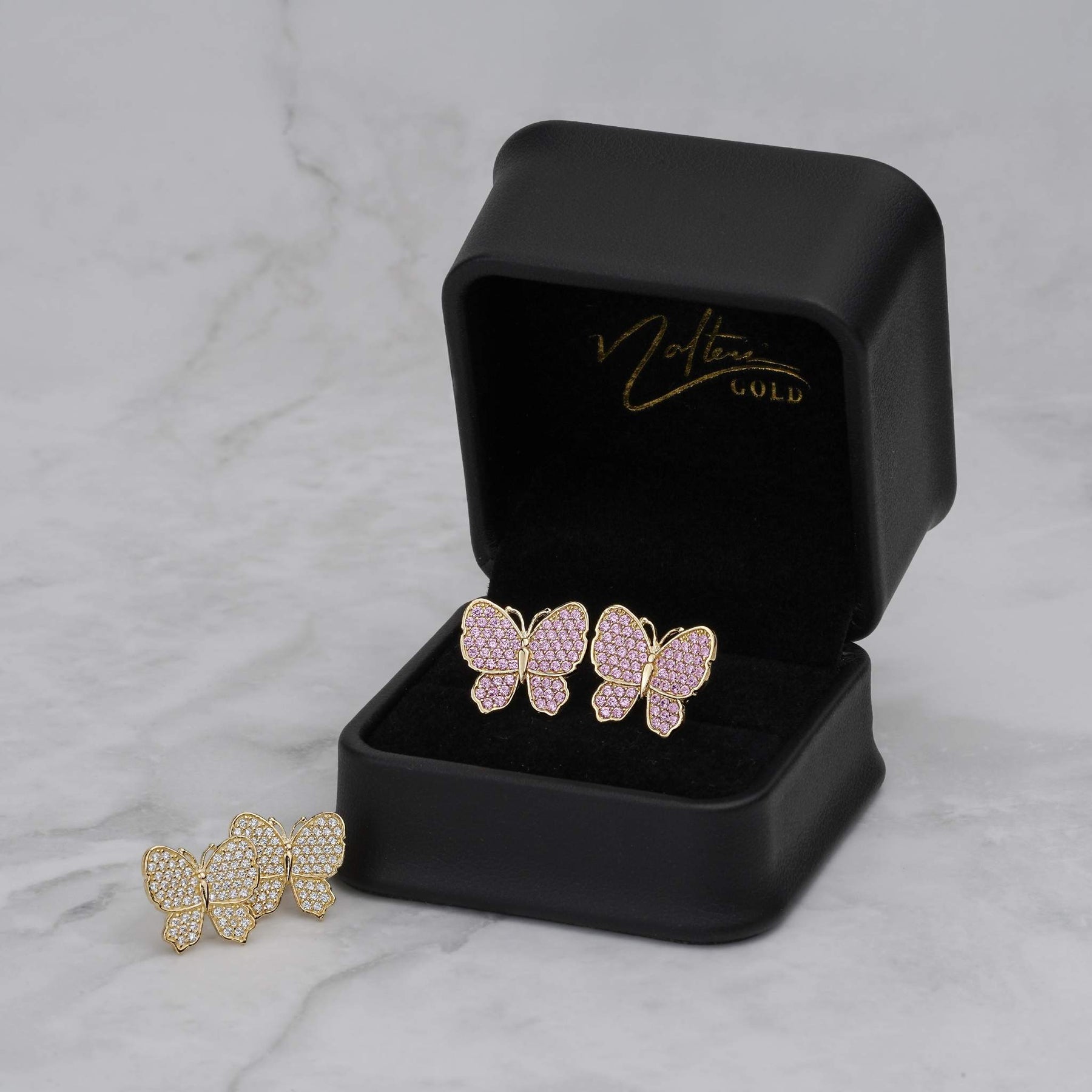 Pink and white gold butterfly stud earrings displayed in a Nolters Gold jewelry box.