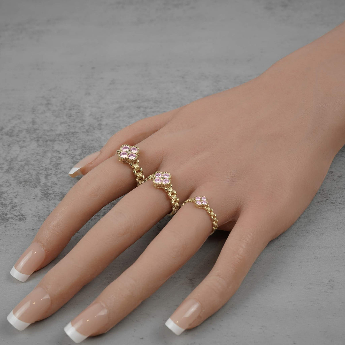 Three sizes of 10k gold luxe clover rollie band rings with pink cubic zirconia.