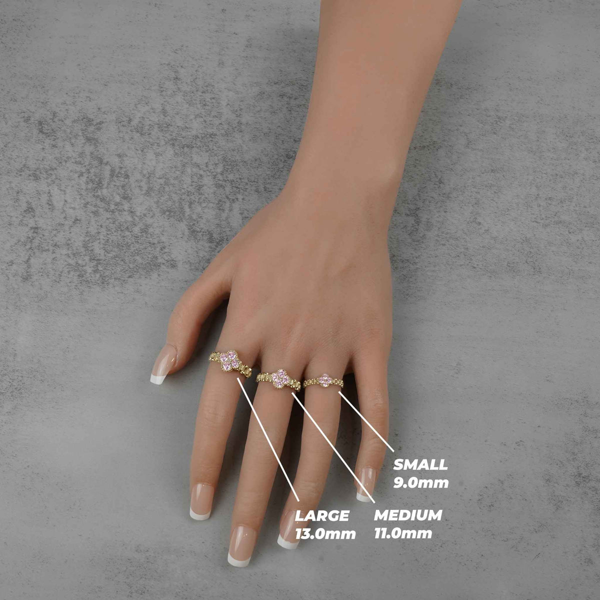 Ring size chart labeling small, medium, and large gold pink clover rings on fingers.