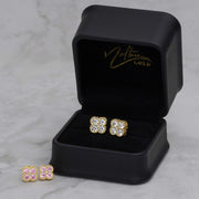 Pink and white CZ clover gold stud earrings inside a black jewelry box.