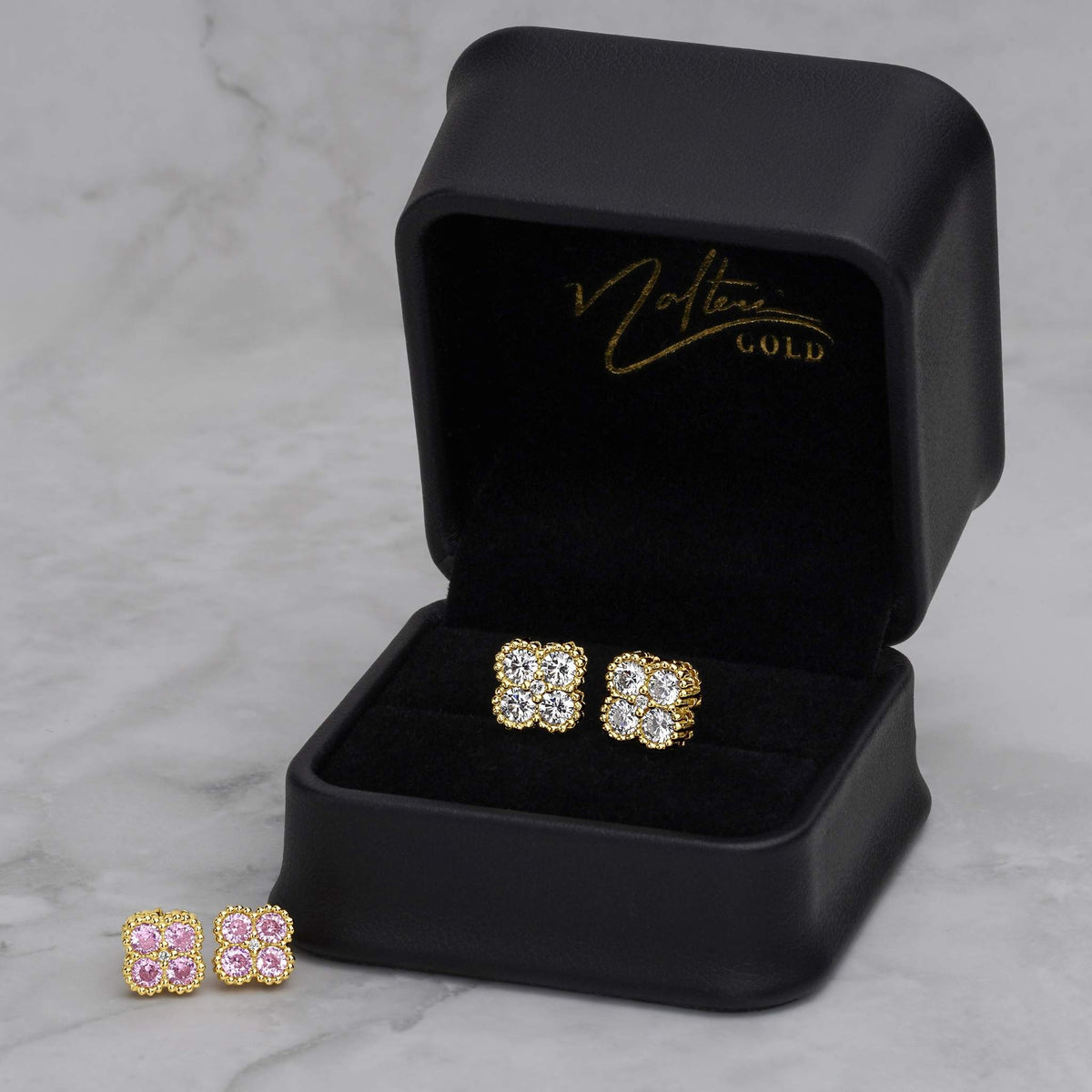 Pink and white CZ clover gold stud earrings inside a black jewelry box.