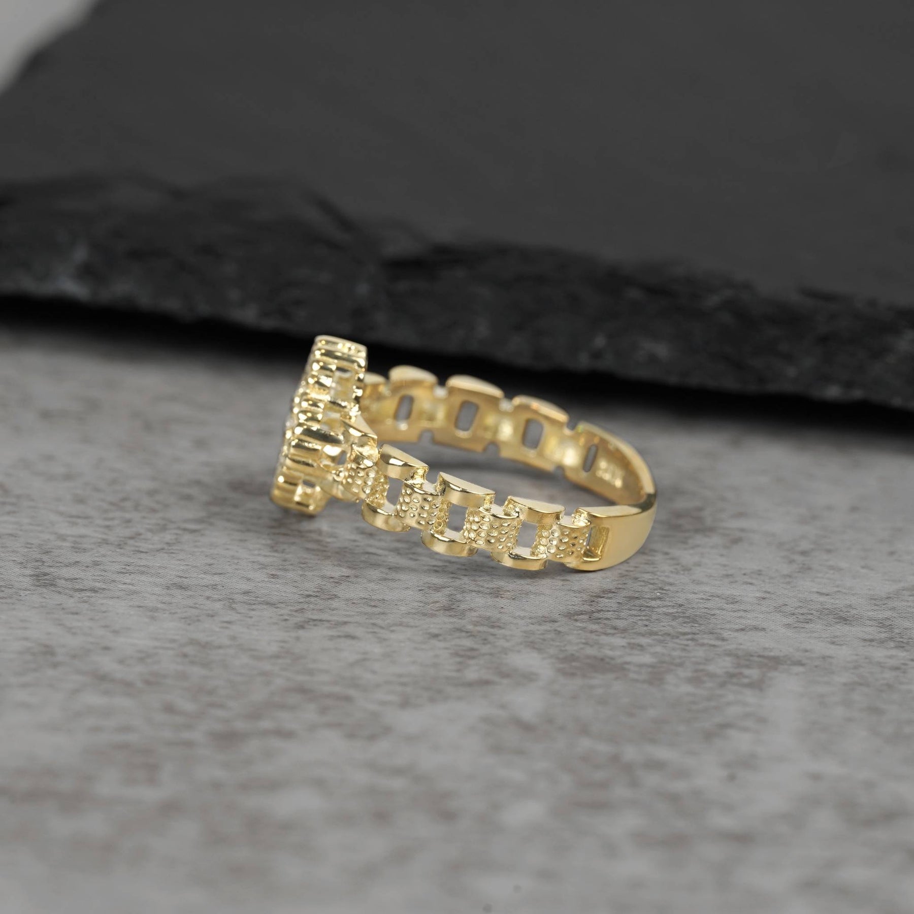 Side profile view of a 10k gold Rolex-style link band ring on stone.