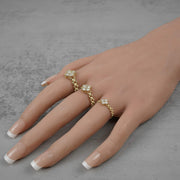 Three gold Rolex-style rings with white clover gemstone clusters worn on a hand.