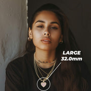 Woman wearing the large 32.0mm gold and pink heart pendant necklace.