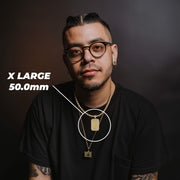 Man in glasses and black shirt showcasing the 50.0mm extra large gold pendant.