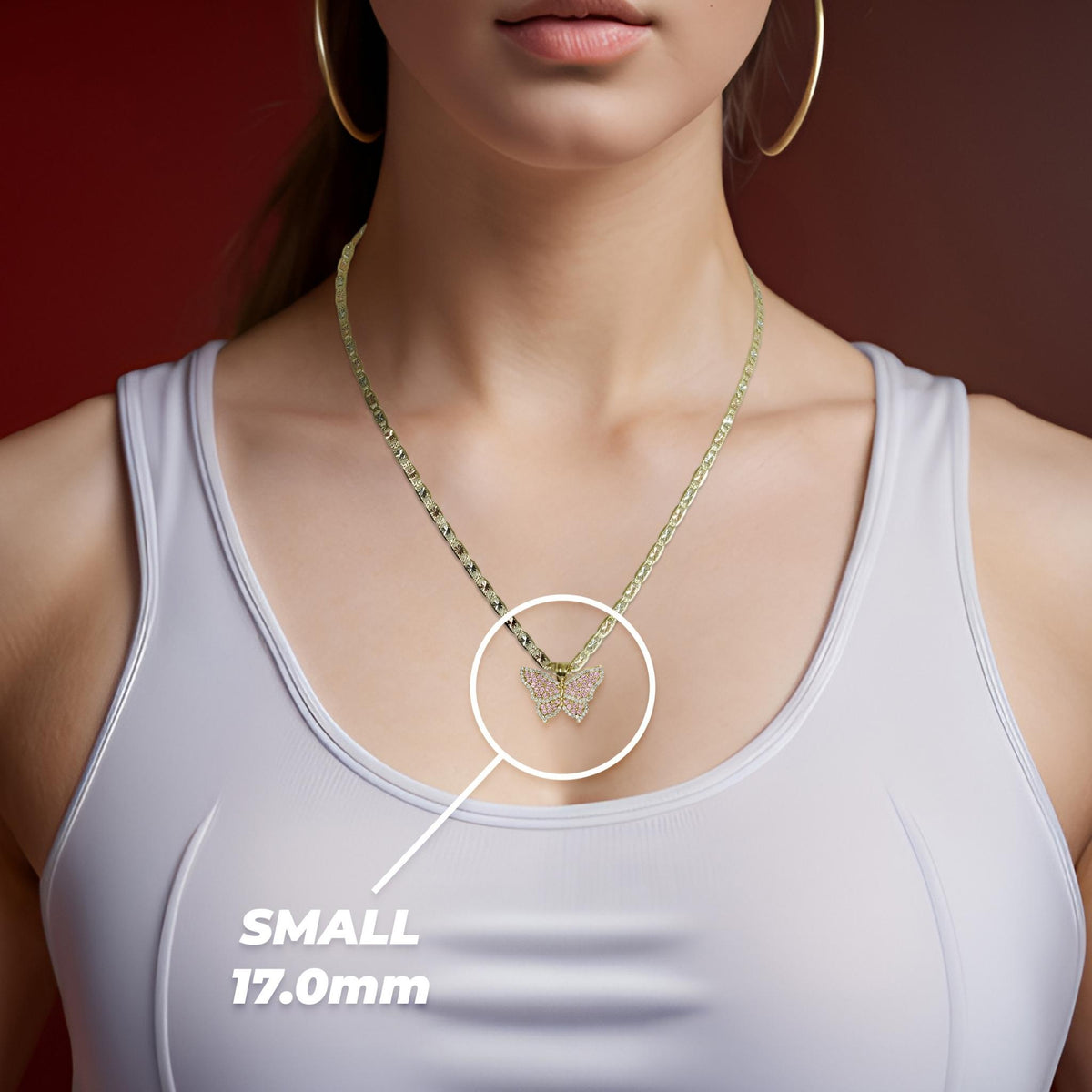 Woman wearing a white top and gold necklace highlighting a small butterfly pendant.