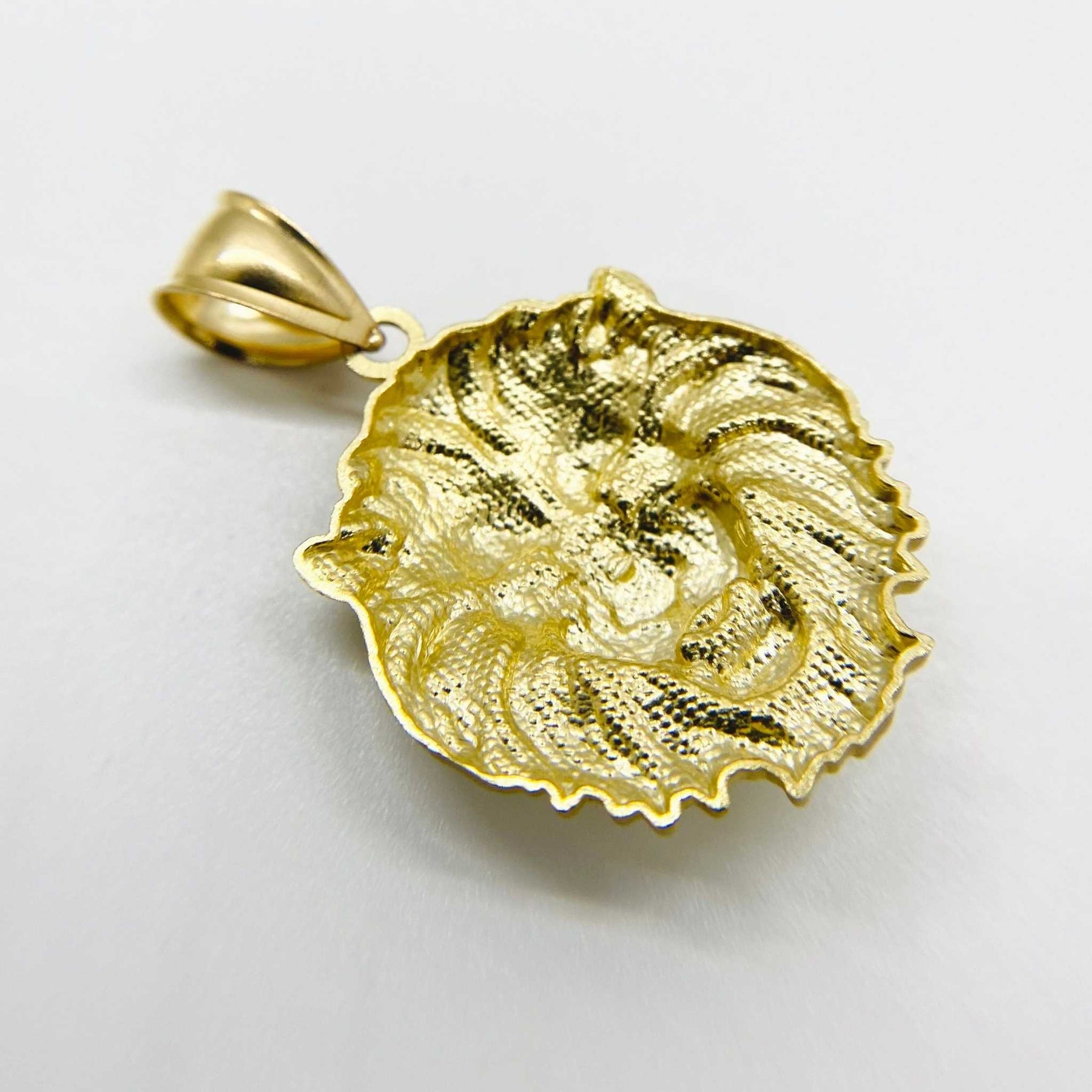 Angled close-up of a textured yellow gold lion head pendant against a white background.