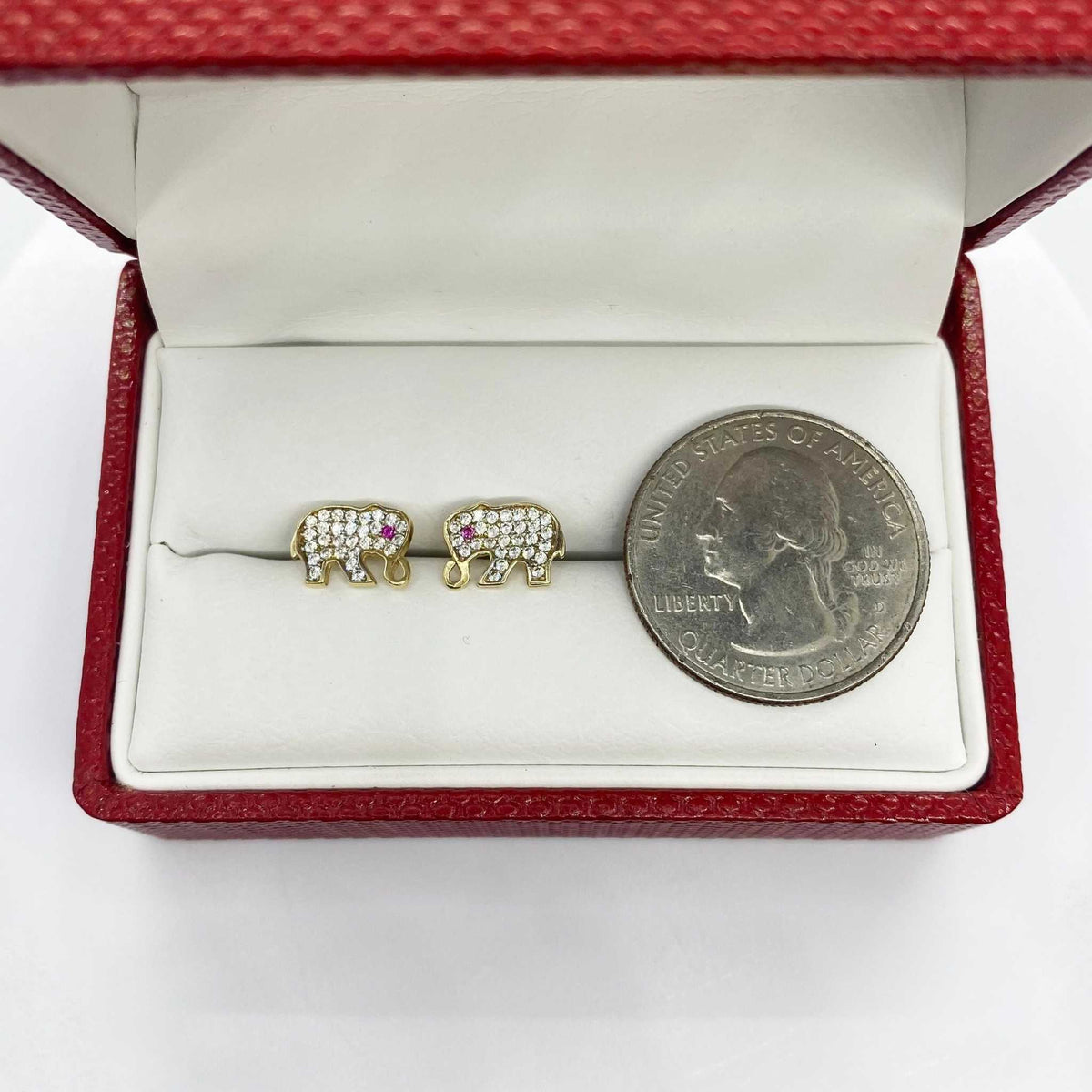 10k gold elephant stud earrings with cubic zirconia in a jewelry box with a quarter.