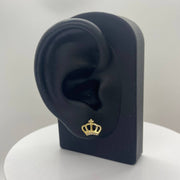 Gold crown earring on a black ear model with a white background.