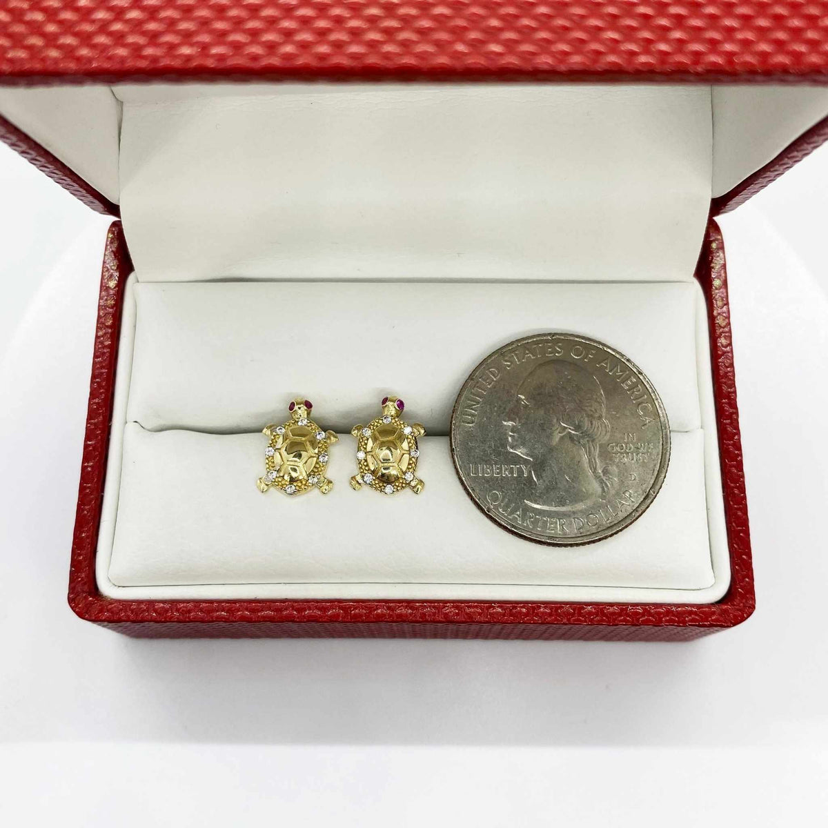 10k gold turtle stud earrings with cubic zirconia and a U.S. quarter for scale.