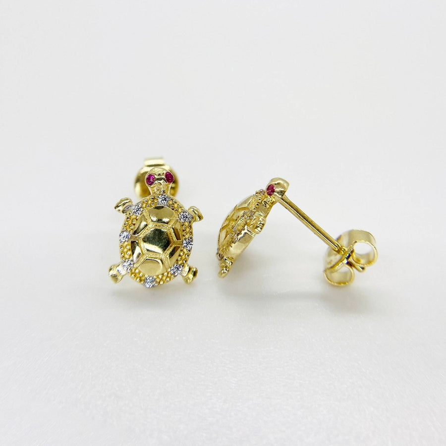 Pair of gold sea turtle stud earrings with sparkling cubic zirconia on white background.